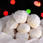 A plate of buttery pecan snowball cookies, dusted with powdered sugar, showcasing their round shape and crunchy pecan filling.