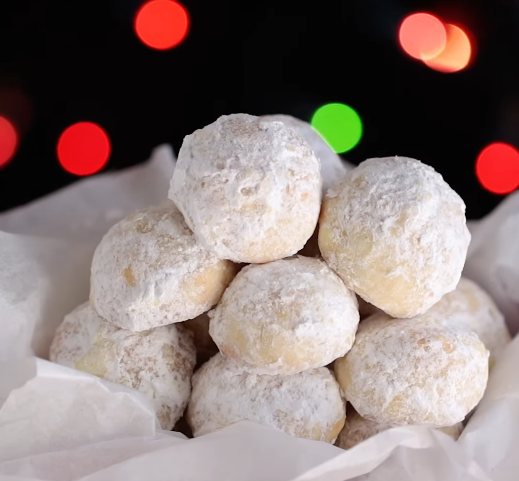 A plate of buttery pecan snowball cookies, dusted with powdered sugar, showcasing their round shape and crunchy pecan filling.